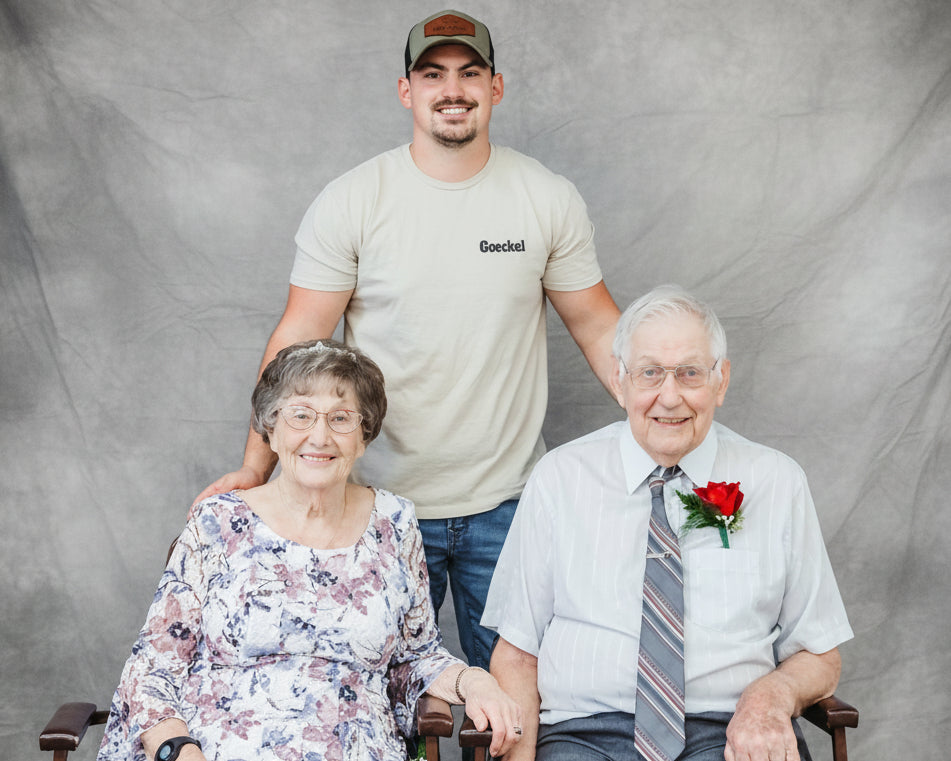 Three people posing together against a blue backdrop